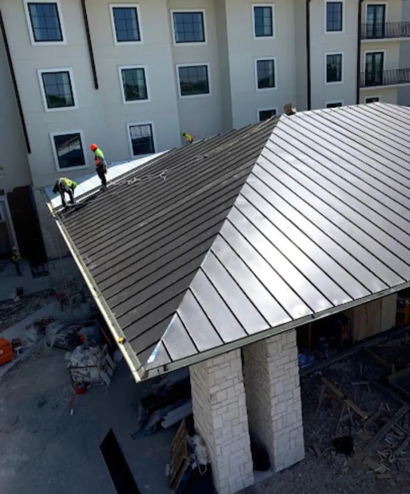 Crew installing standing seam metal roof panels on a commercial project in Alcoa